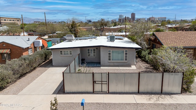 view of front of home featuring stucco siding, a fenced front yard, central AC, solar panels, and a gate
