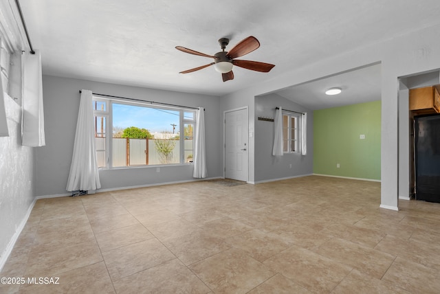 spare room with ceiling fan and baseboards