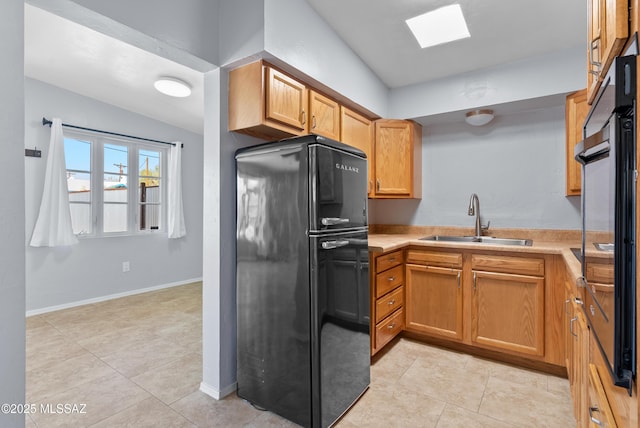 kitchen featuring baseboards, a sink, light countertops, freestanding refrigerator, and lofted ceiling