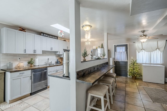 kitchen featuring white cabinetry, decorative backsplash, a sink, dark countertops, and appliances with stainless steel finishes