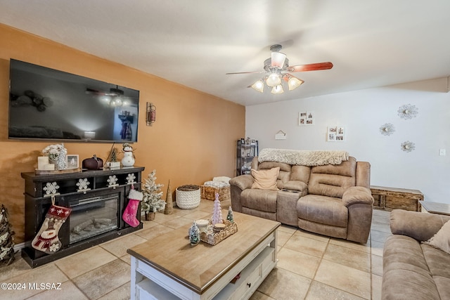 living room with light tile patterned flooring, a glass covered fireplace, and ceiling fan