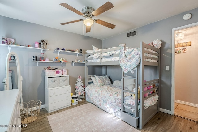 bedroom featuring wood finished floors, baseboards, ceiling fan, and visible vents