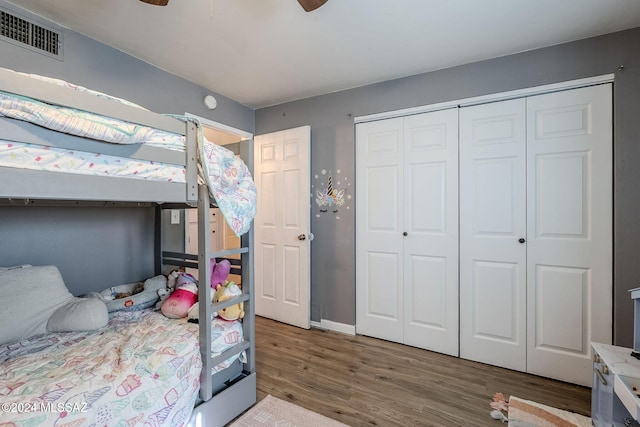 bedroom with a closet, wood finished floors, baseboards, visible vents, and ceiling fan