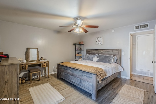 bedroom with baseboards, visible vents, and wood finished floors