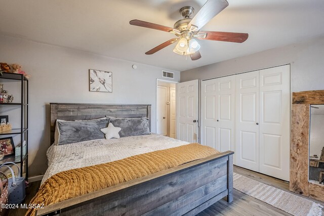 bedroom with visible vents, a closet, wood finished floors, and a ceiling fan