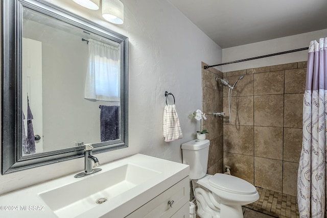 bathroom featuring a tile shower, toilet, and vanity