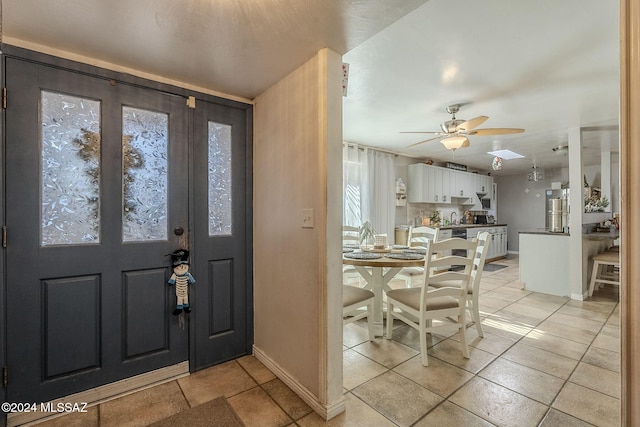foyer featuring a ceiling fan, light tile patterned floors, and baseboards