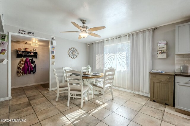 dining space with baseboards, light tile patterned floors, and a ceiling fan