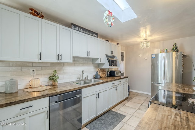 kitchen featuring stainless steel appliances, decorative backsplash, a sink, wood counters, and a skylight