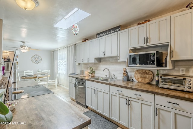 kitchen featuring tasteful backsplash, stainless steel appliances, a sink, a skylight, and butcher block counters