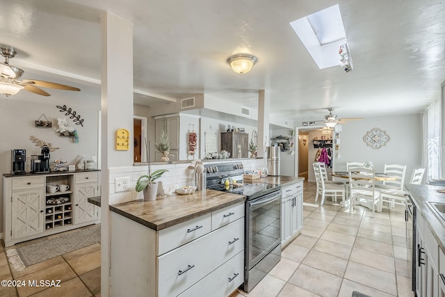 kitchen featuring light tile patterned floors, stainless steel appliances, a skylight, and ceiling fan