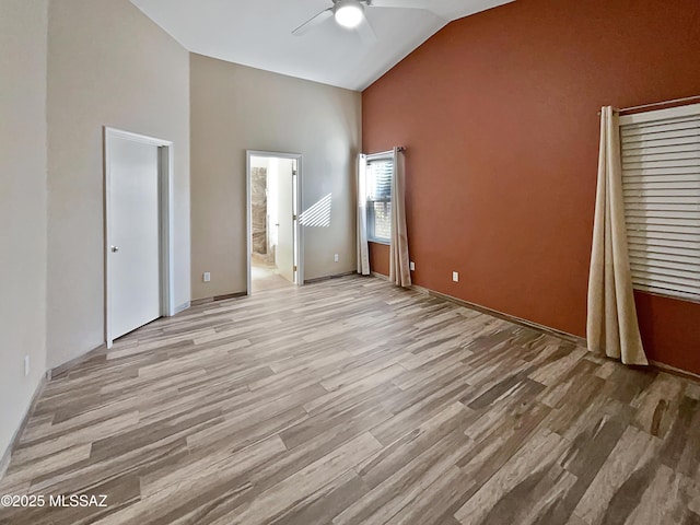 unfurnished bedroom featuring ensuite bathroom, high vaulted ceiling, ceiling fan, and light wood-type flooring