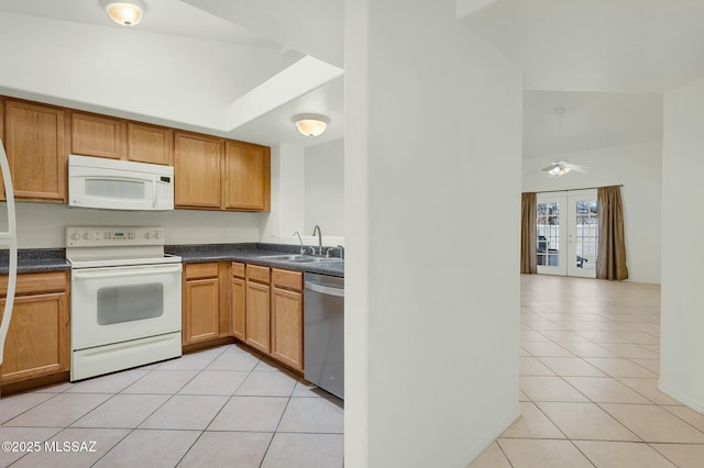 kitchen with white appliances, dark countertops, a sink, and light tile patterned floors