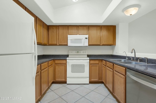 kitchen featuring light tile patterned flooring, white appliances, brown cabinets, dark countertops, and a sink