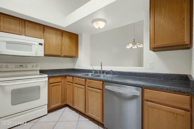 kitchen featuring white appliances, dark countertops, a sink, an inviting chandelier, and light tile patterned floors
