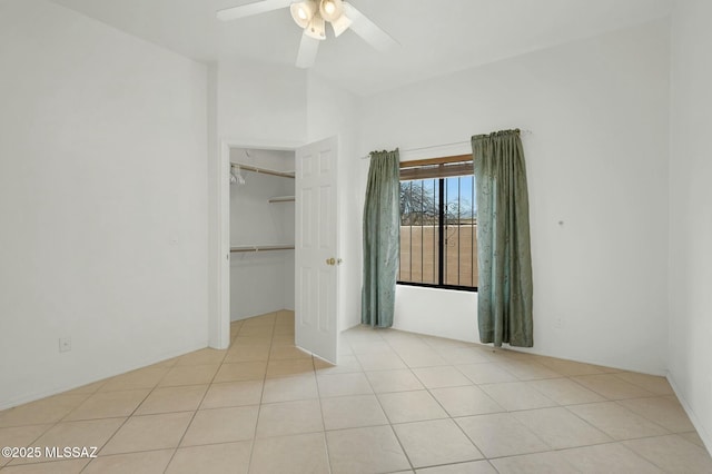 unfurnished bedroom with lofted ceiling, a spacious closet, tile patterned floors, a ceiling fan, and a closet