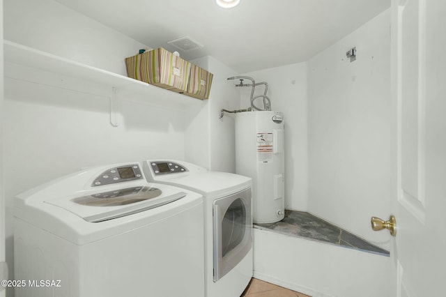 washroom with electric water heater, independent washer and dryer, light tile patterned floors, visible vents, and laundry area