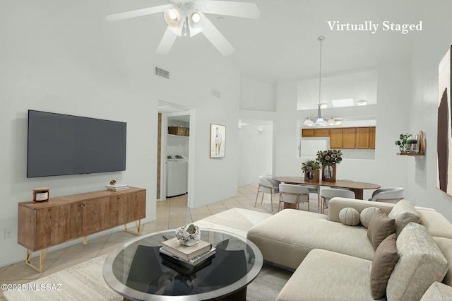 living room featuring light tile patterned flooring, high vaulted ceiling, visible vents, ceiling fan, and washer / dryer