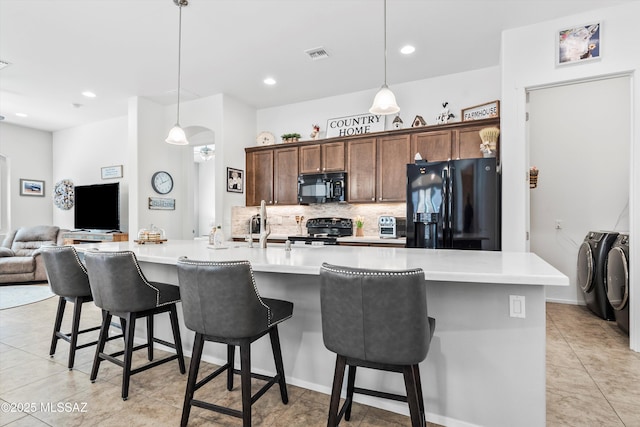 kitchen featuring visible vents, separate washer and dryer, open floor plan, black appliances, and backsplash