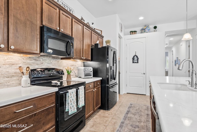 kitchen featuring light countertops, a sink, black appliances, and decorative backsplash