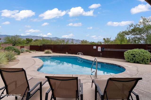 view of pool featuring fence, a patio, a mountain view, and a fenced in pool