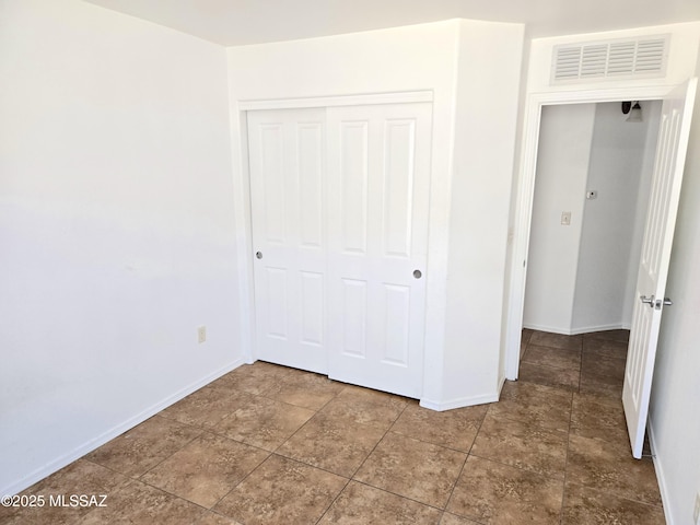 unfurnished bedroom featuring baseboards, visible vents, and a closet