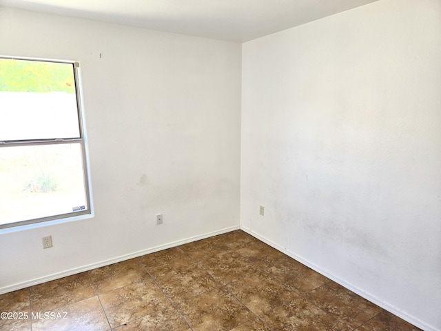 spare room with a wealth of natural light and baseboards