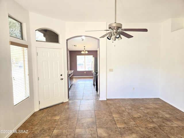 interior space featuring arched walkways, visible vents, a ceiling fan, and baseboards