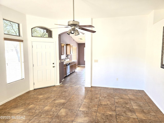 entryway featuring arched walkways, a ceiling fan, and baseboards