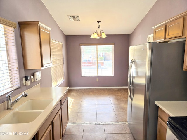 kitchen with lofted ceiling, light countertops, a sink, freestanding refrigerator, and a notable chandelier
