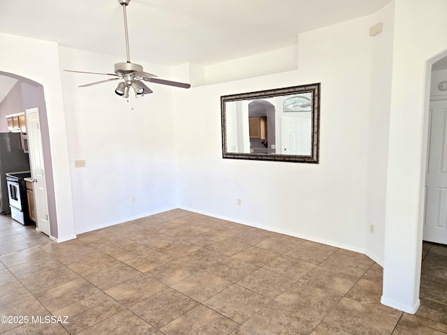 spare room with ceiling fan, arched walkways, and baseboards