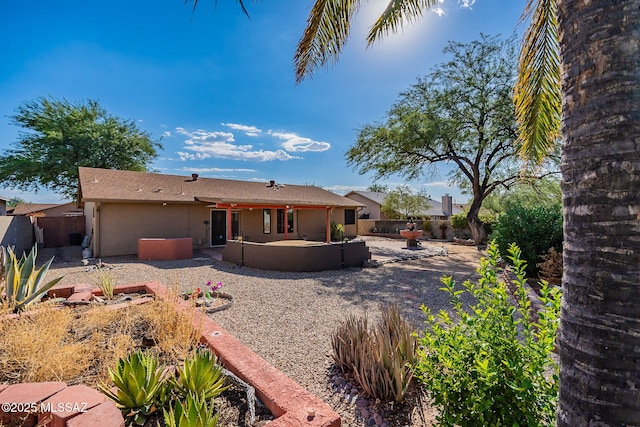 rear view of property featuring fence, stucco siding, and a patio area