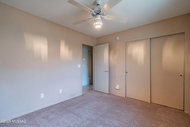 unfurnished bedroom featuring baseboards, a closet, light colored carpet, and ceiling fan