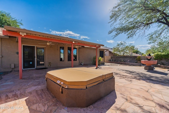 view of patio / terrace featuring ceiling fan, fence, and a hot tub