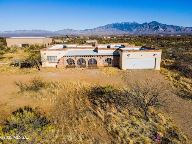 view of front of home with a chimney, stucco siding, an attached garage, and a mountain view