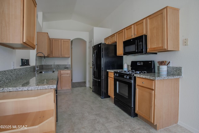 kitchen with a sink, light stone countertops, lofted ceiling, black appliances, and arched walkways