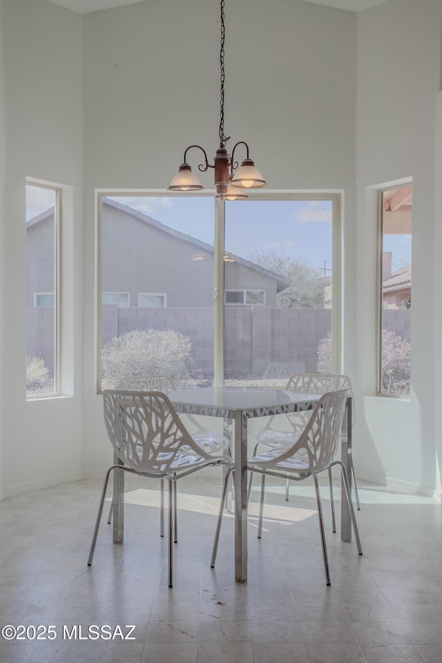 dining area featuring baseboards and a towering ceiling