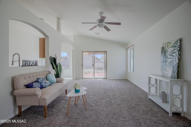 carpeted living room with a ceiling fan, arched walkways, baseboards, and lofted ceiling