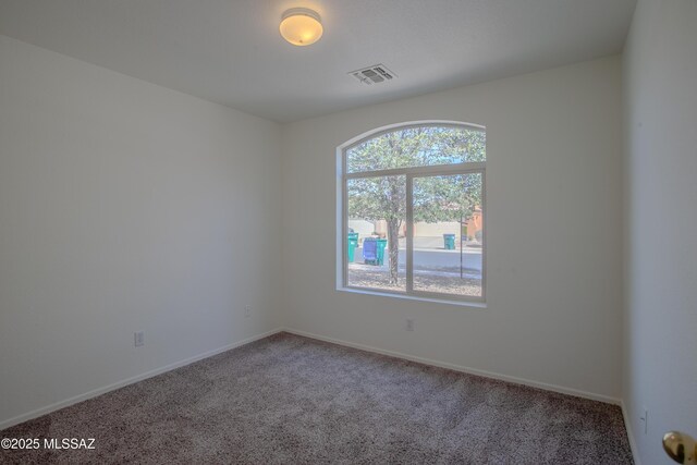 spare room featuring baseboards, visible vents, and carpet flooring