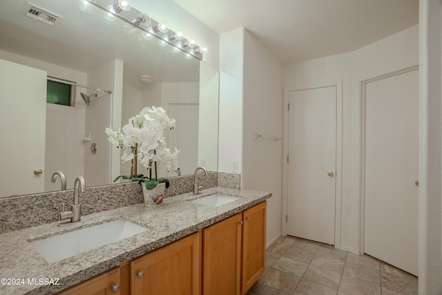 full bathroom with double vanity, a sink, walk in shower, and visible vents