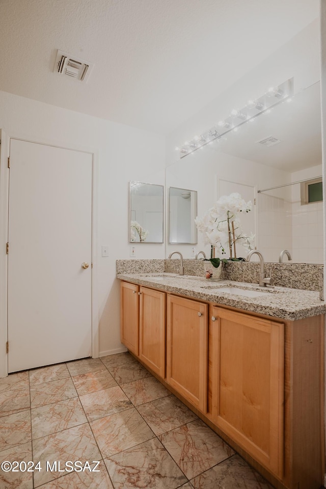 bathroom with double vanity, a sink, walk in shower, and visible vents