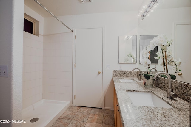 bathroom with double vanity, a sink, and a stall shower