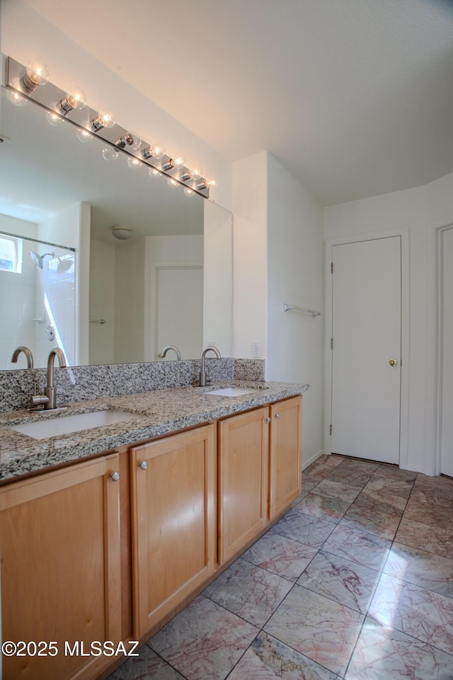bathroom featuring marble finish floor, double vanity, and a sink