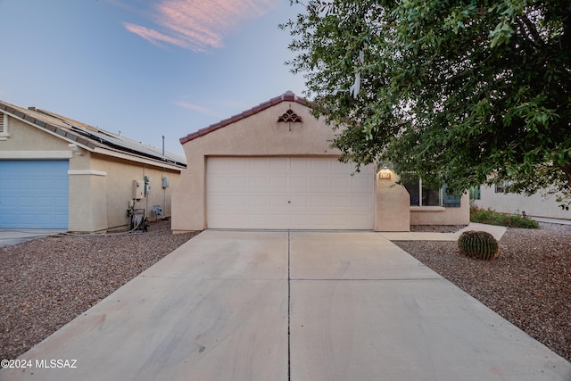 view of front of property with stucco siding, a tile roof, a garage, and concrete driveway