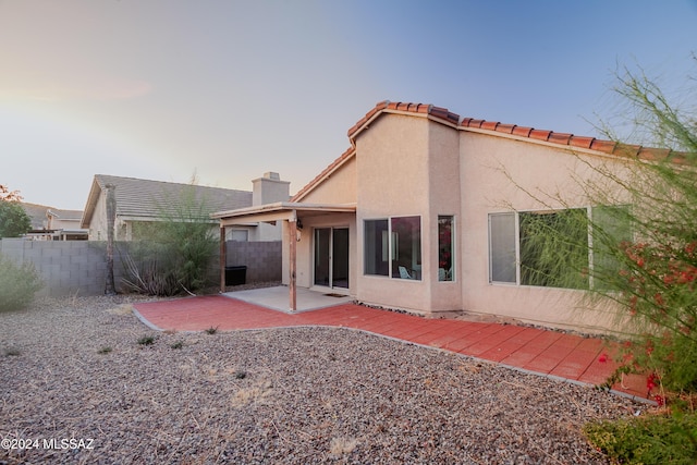 rear view of property with a fenced backyard, a tile roof, stucco siding, and a patio