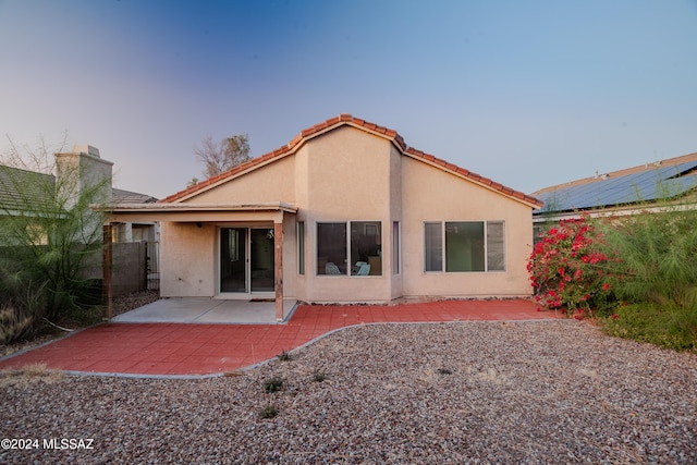 rear view of house with a tile roof, stucco siding, a patio, and a chimney