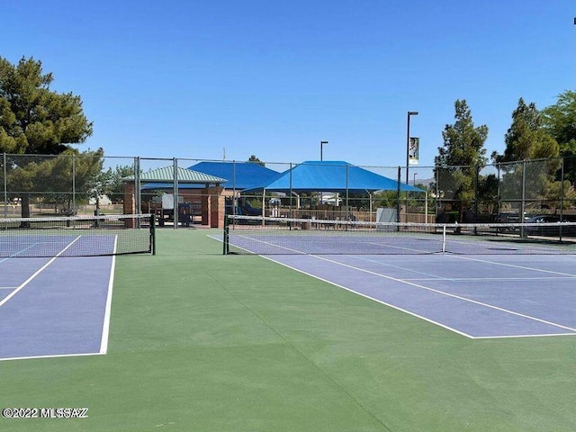 view of tennis court with community basketball court and fence