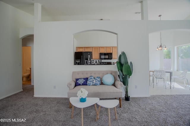 sitting room with high vaulted ceiling, baseboards, arched walkways, carpet, and an inviting chandelier