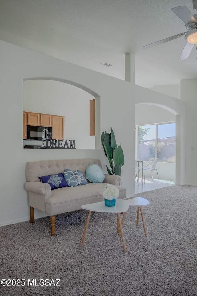 living room with vaulted ceiling, visible vents, carpet floors, and a ceiling fan