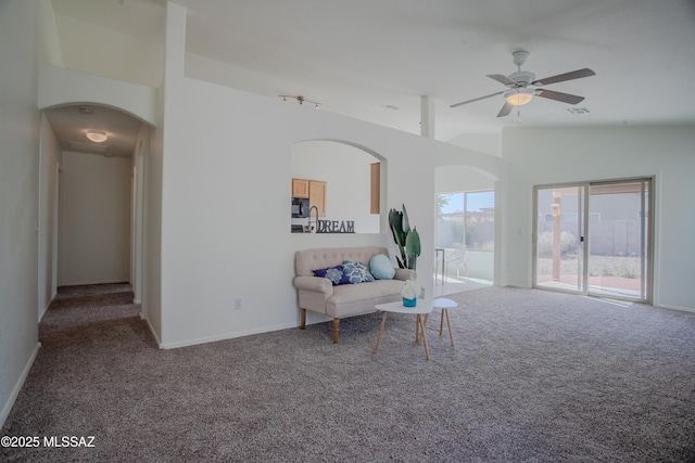 sitting room featuring vaulted ceiling, carpet flooring, a ceiling fan, visible vents, and arched walkways